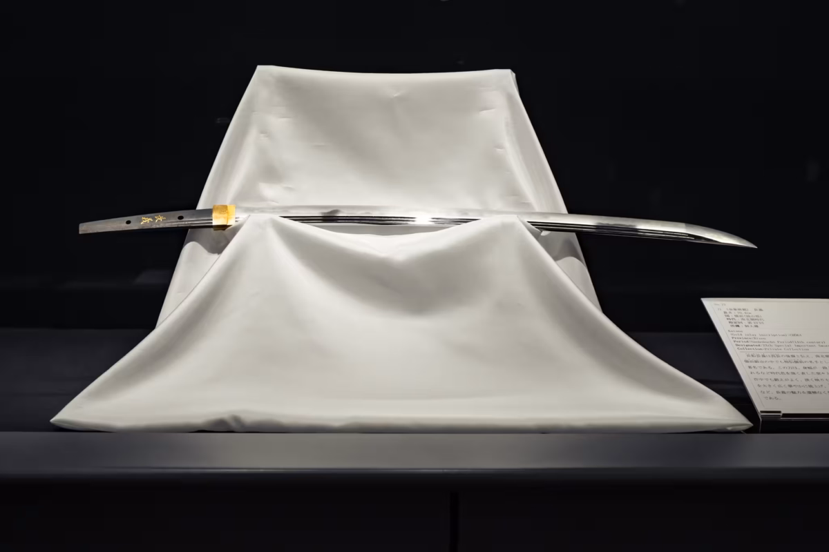 A 14th-century katana on a display pedestal draped with a white cloth.