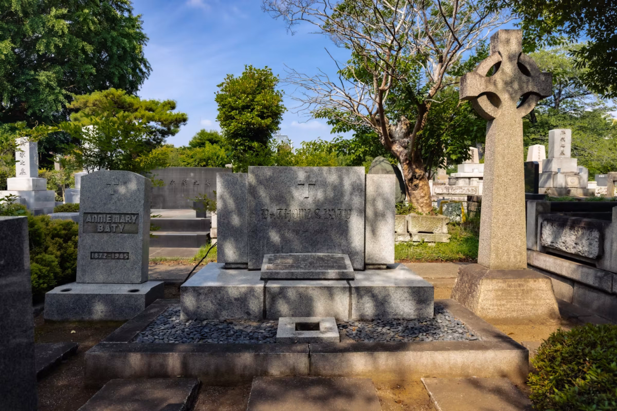 Three graves with graves and trees behind.