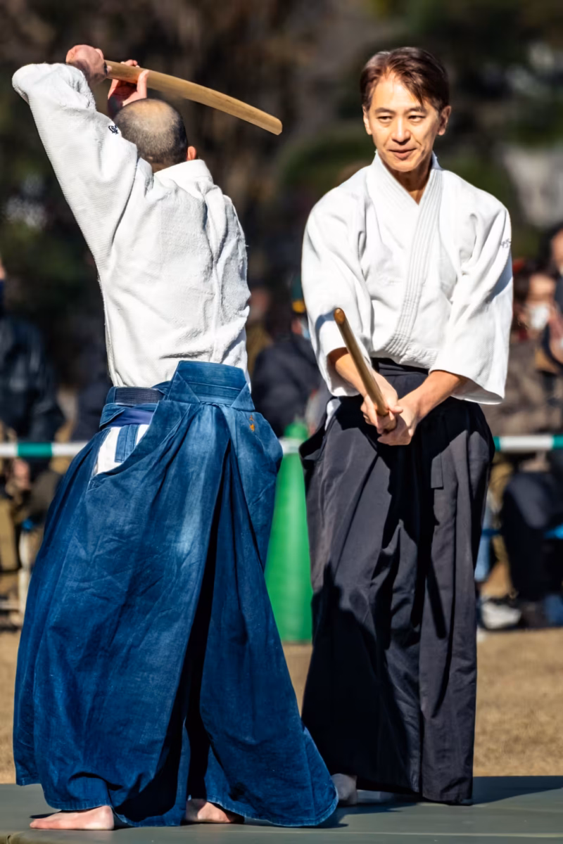 Two aikidokas practice with wooden swords.