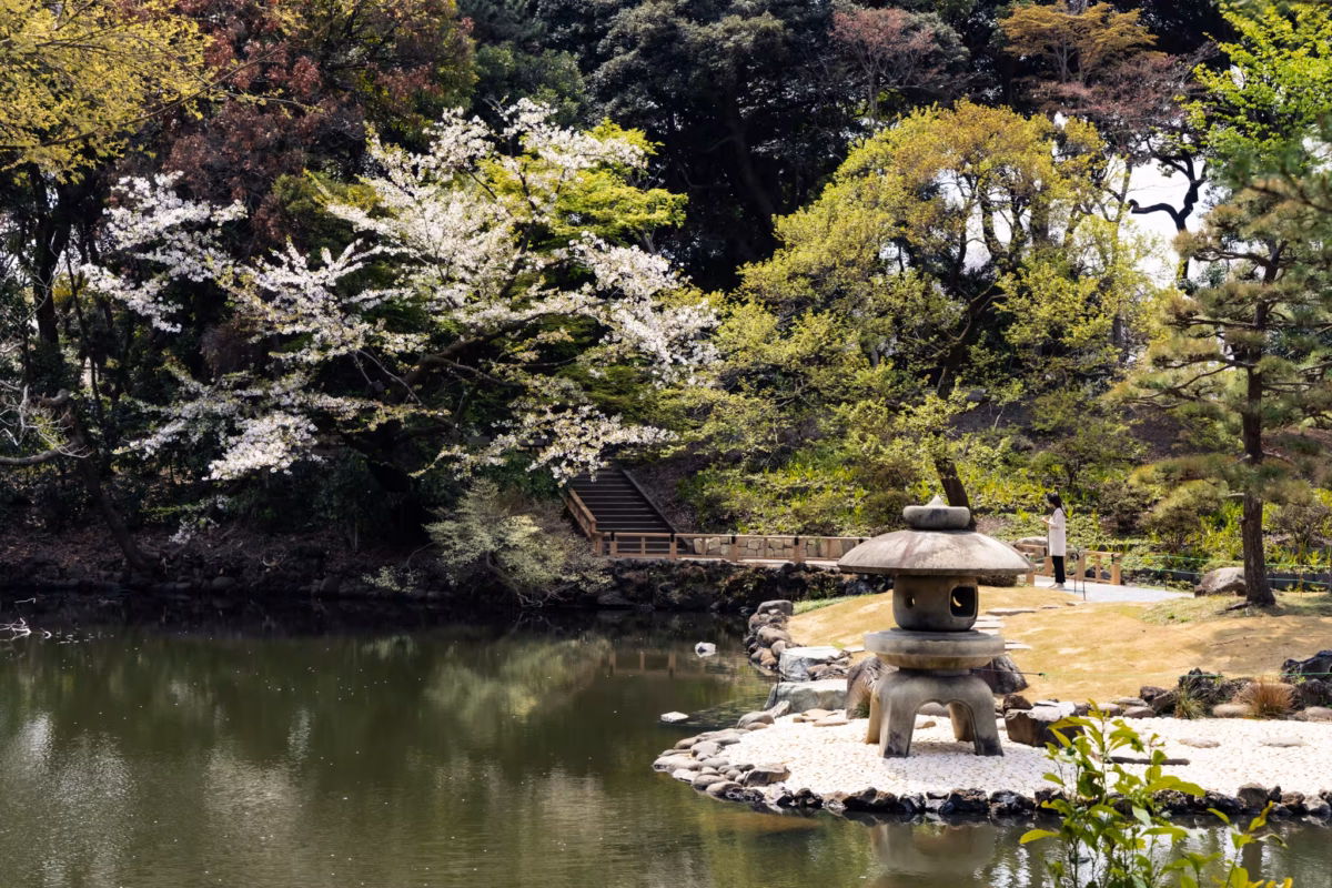 A large stone lantern sits next to a pond.