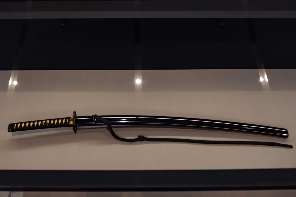 A tachi sword in a scabbard in a display case.