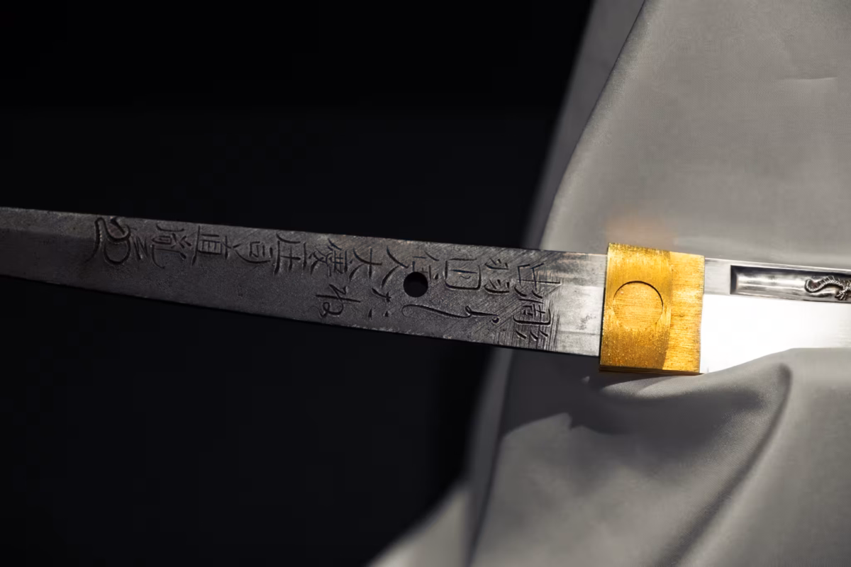 A katana with a hole sits on a white display pedestal.