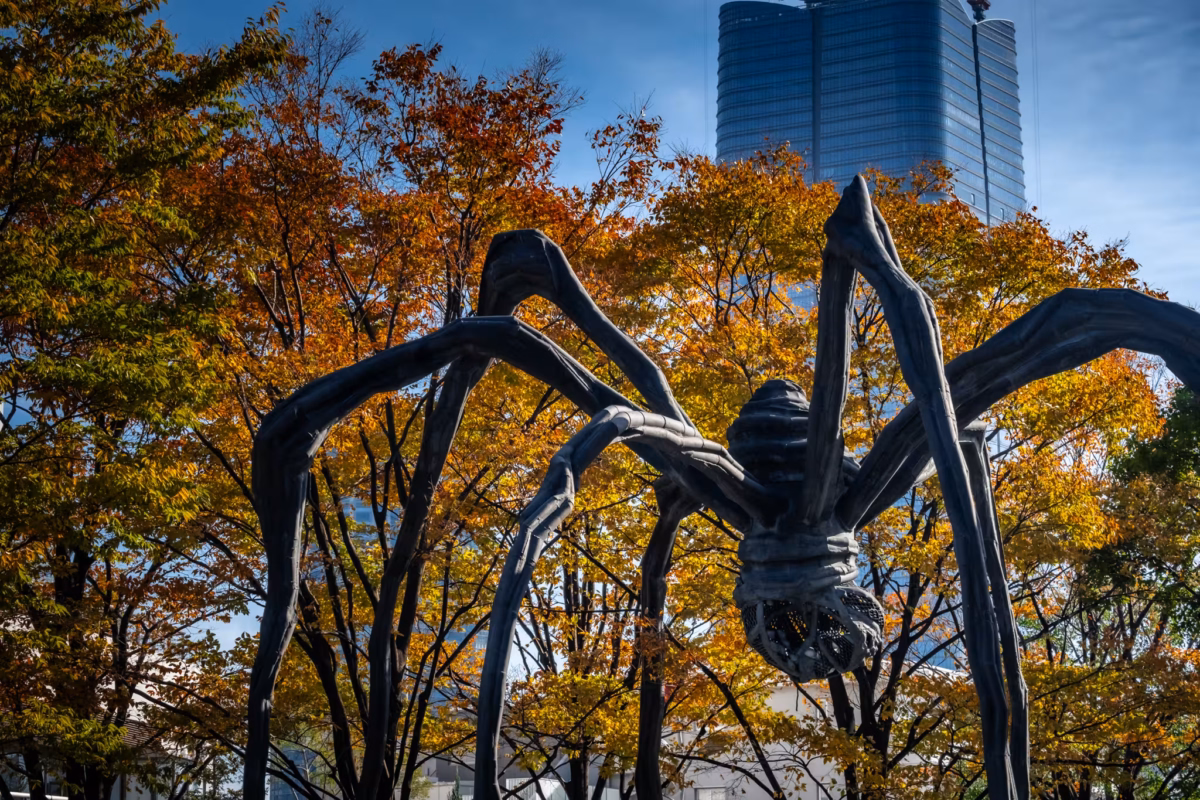 The Maman spider with trees and the Azabudai Hills skyscraper beyond.