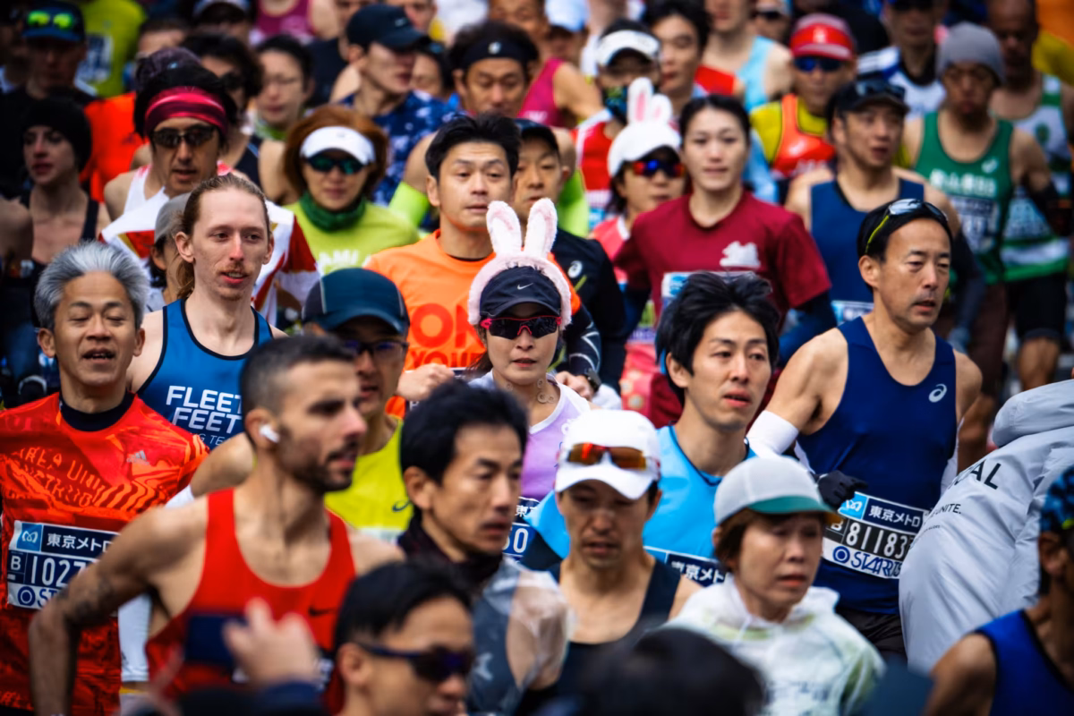 A woman wear bunny ears in the middle of a group of runners.