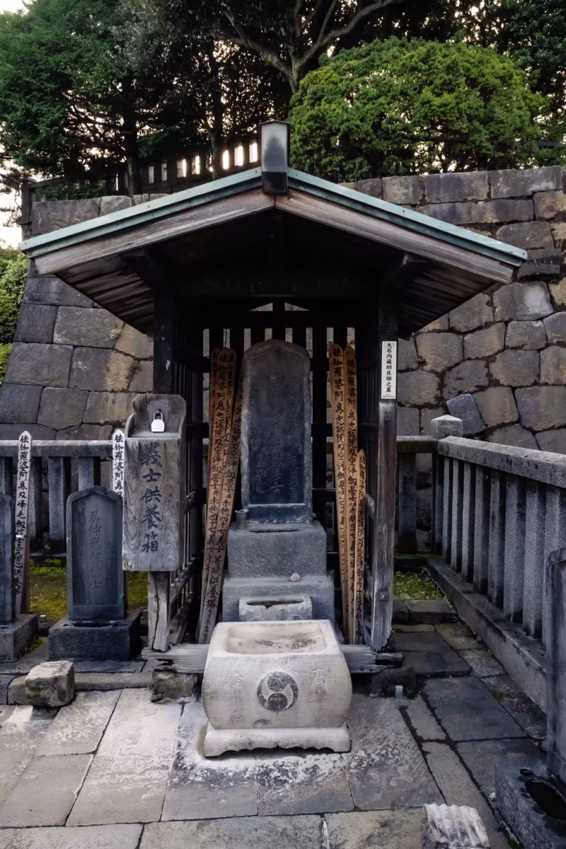 A grave under a small wooden roof.