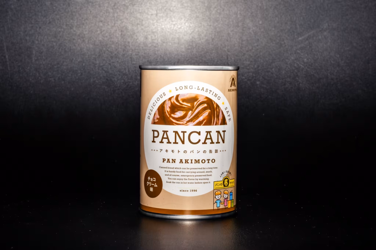 A can of Akimono canned bread sits before a black background.