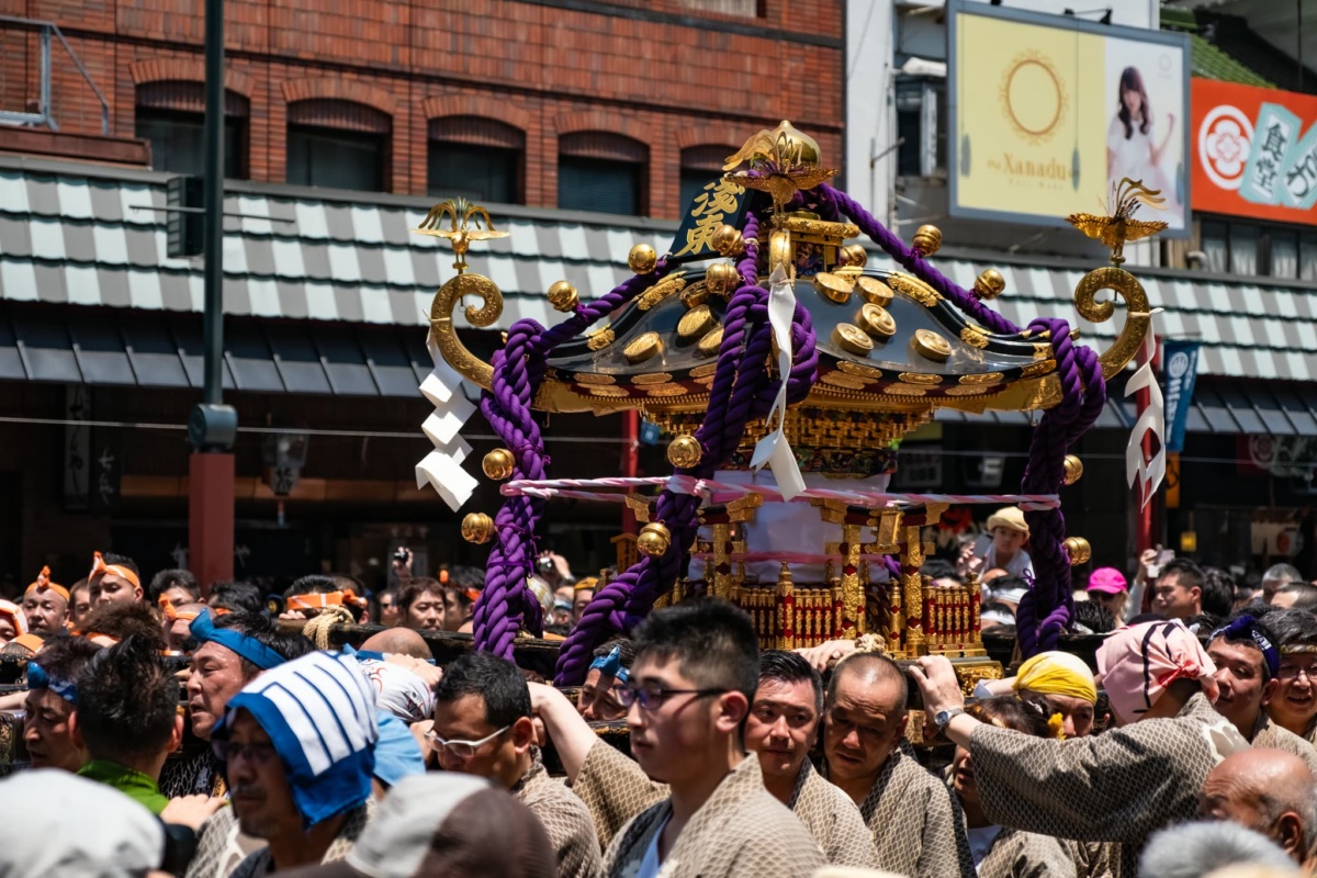 People in traditional wear carry a portable shrine through Tokyo streets.