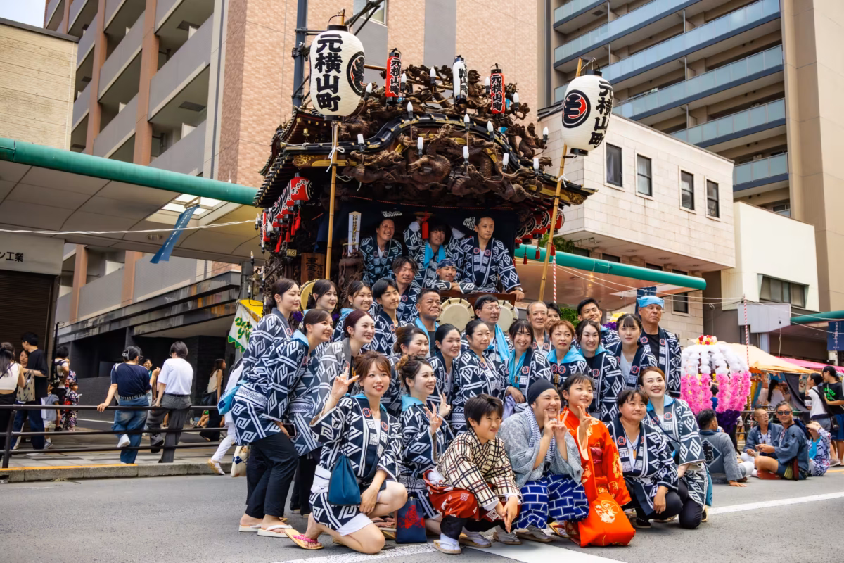 People in traditional festival clothes pose for a photo in front of a float.