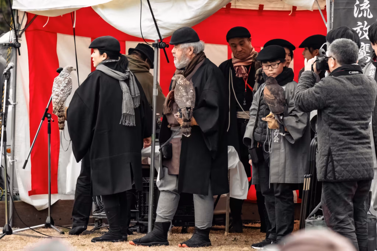 A group of falconers with their birds in a red and white tent.