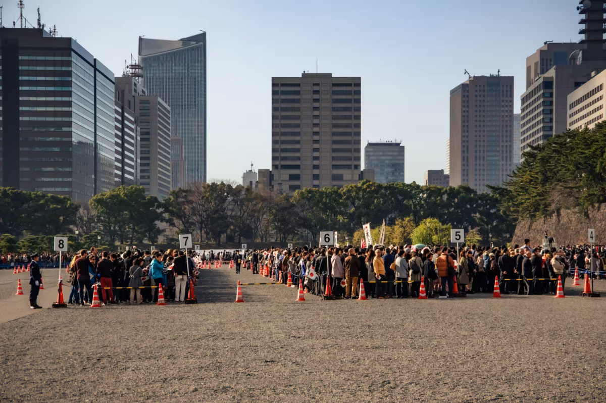 People wait in a gravel square to enter the Imperial Palace for the Emperor's 83rd birthday.