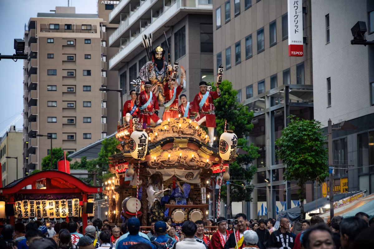 People in red happi coats on a float cherry others on below.