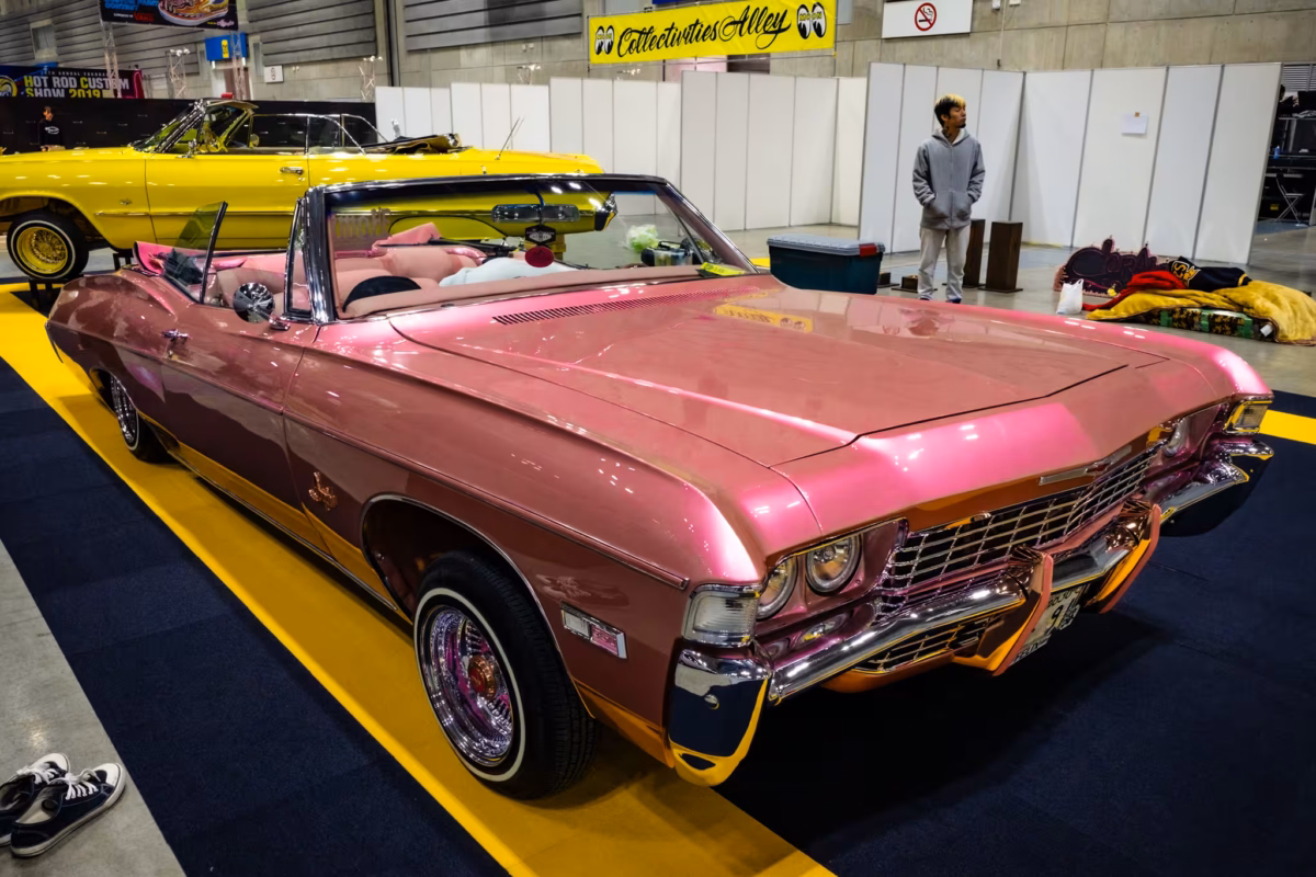 A man looks at a pink Chevrolet convertible.