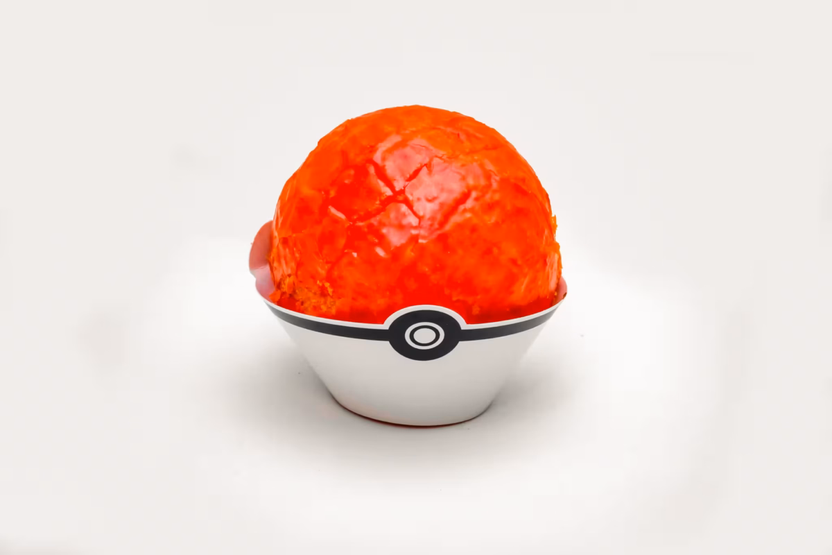 A red Poke Ball dont sits in a white cardboard cup on a white background.