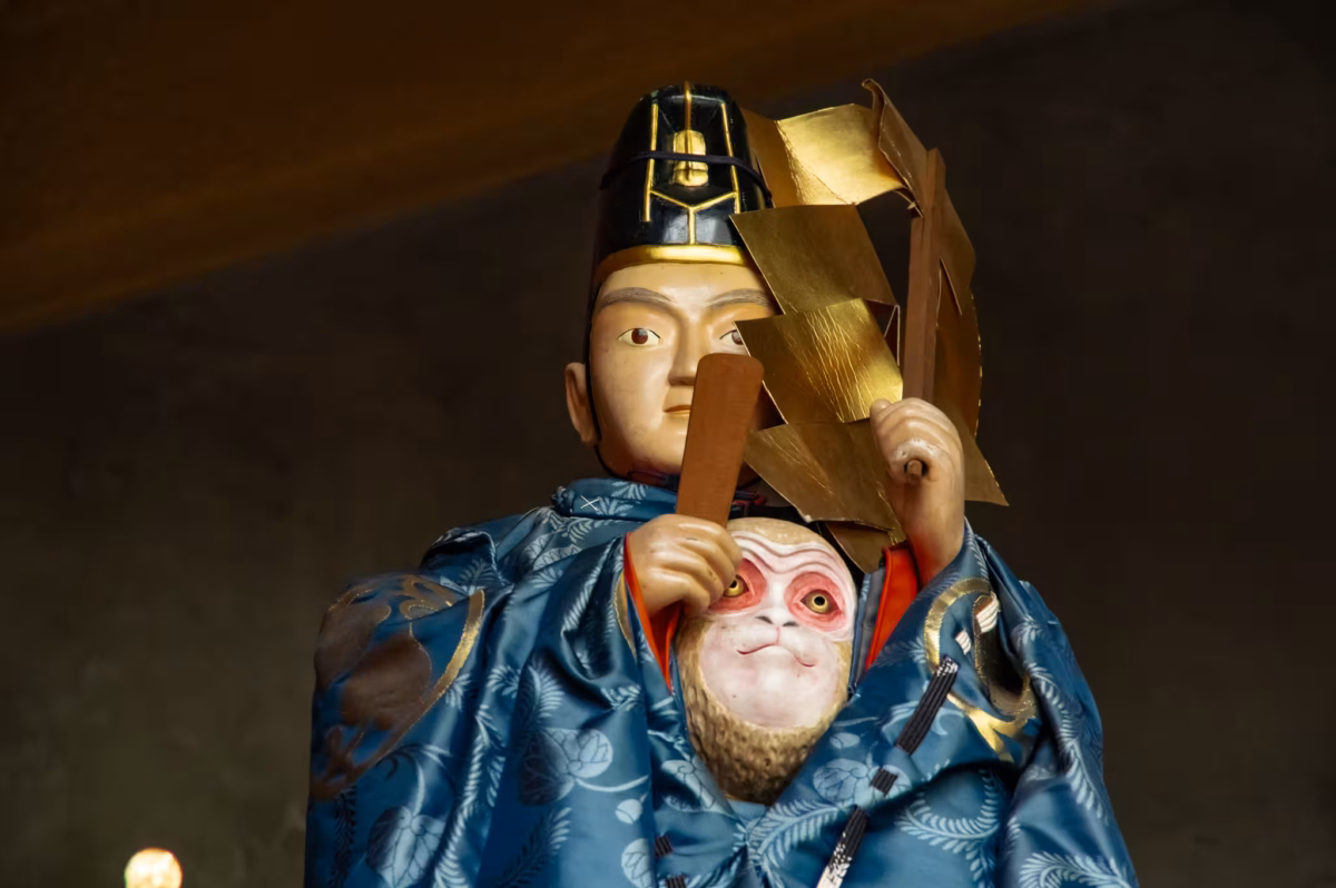 A statue of a shinto priest hides a monkey in his robe.