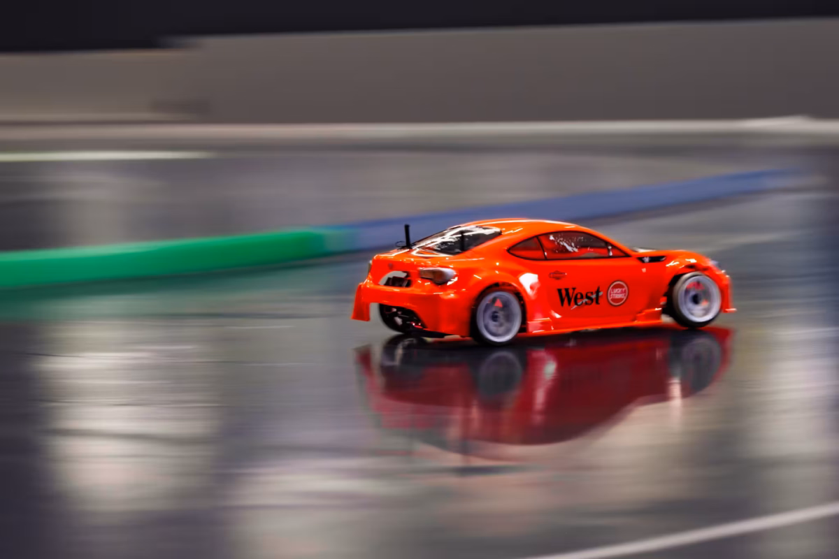 A red RC car speeds around a track with a blurred background.
