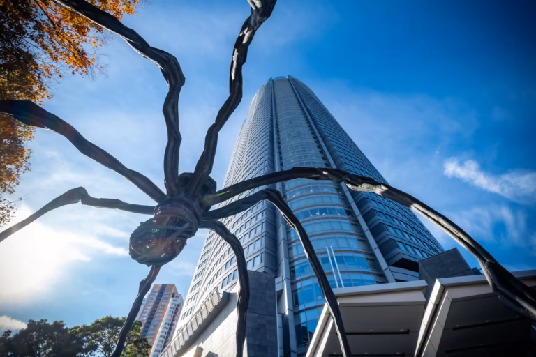 Looking up at the belly of the Maman spider with the Roppongi Hills skyscraper behind.