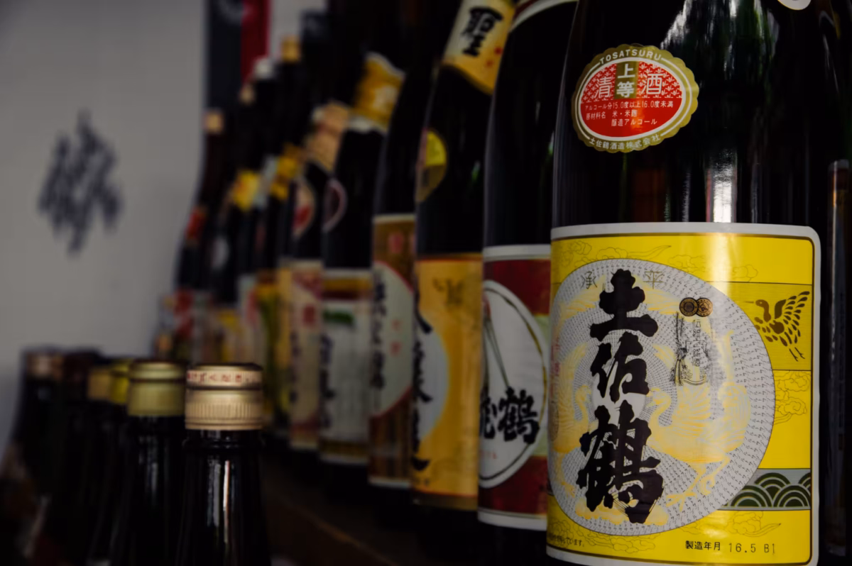 A line of sake bottles blur into the distance.