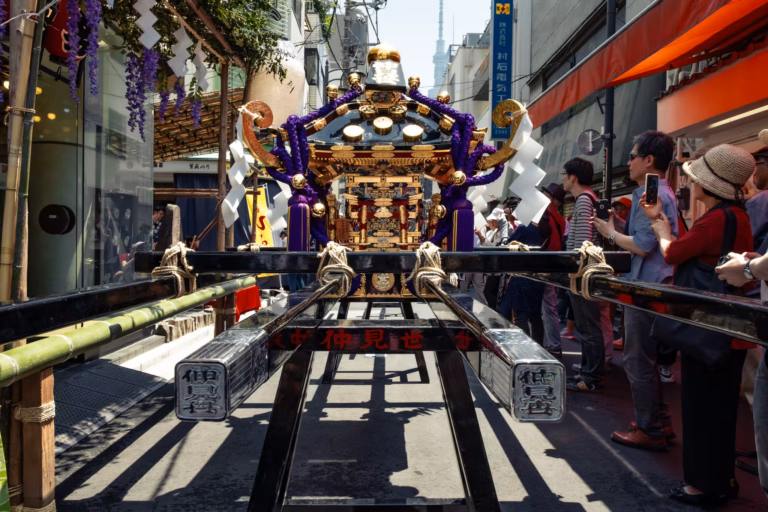 A mikoshi rests on a trestle with people taking photos.
