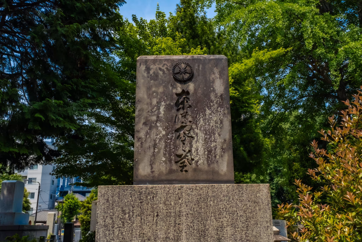 The tower of Hideki Tojo's grave with trees behind at Zoshigaya Cemetery.
