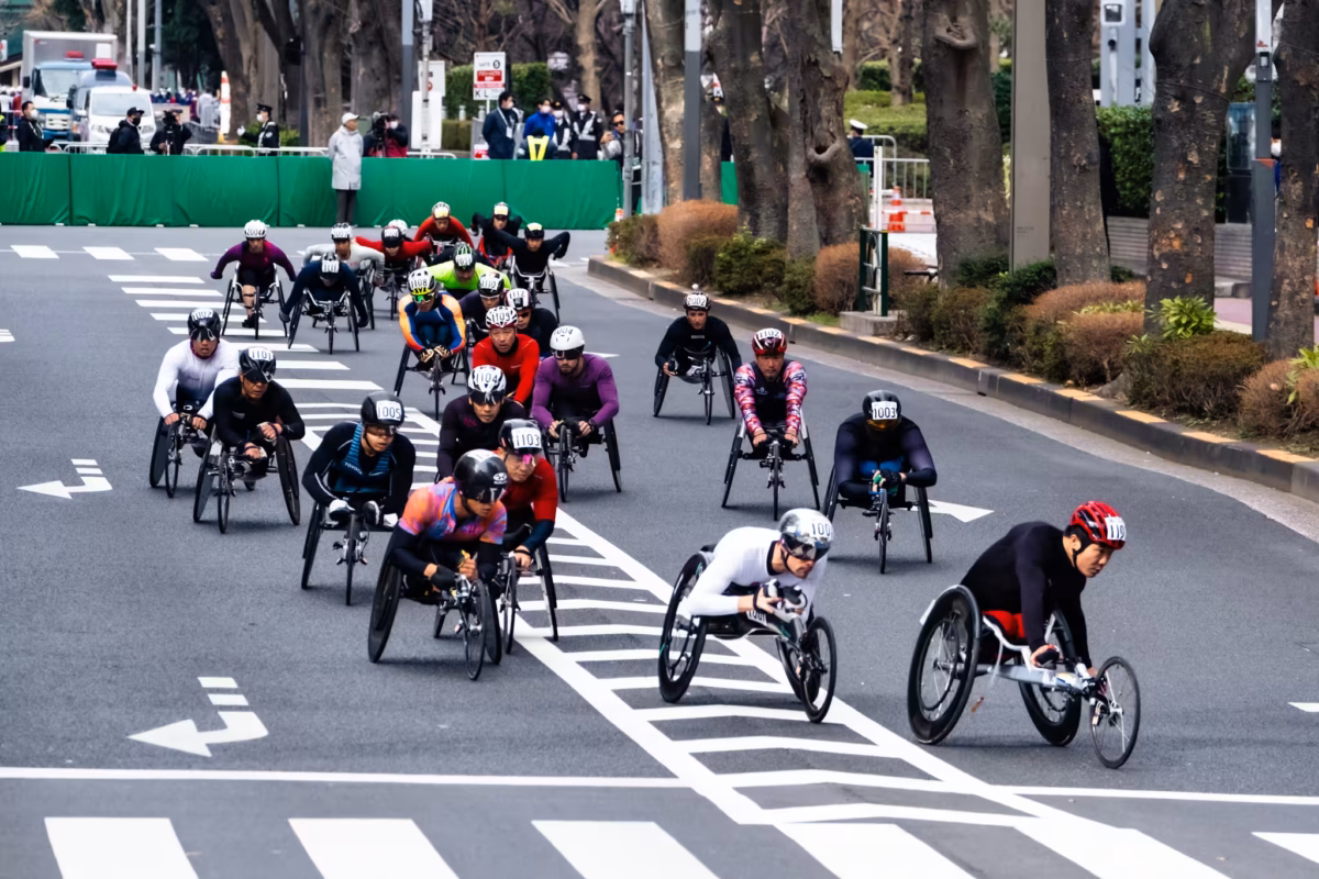 Helmeted wheelchair marathon atheletes race down a Tokyo street.