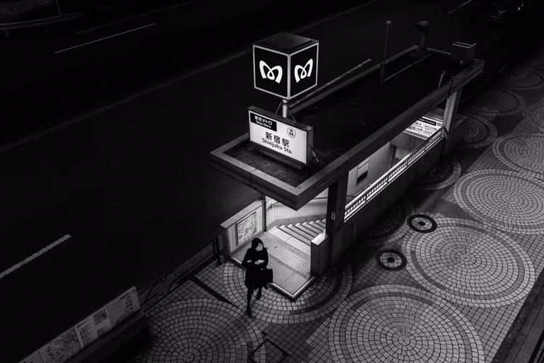 A women leaves a Shinjuku subway exit onto an empty street at night.