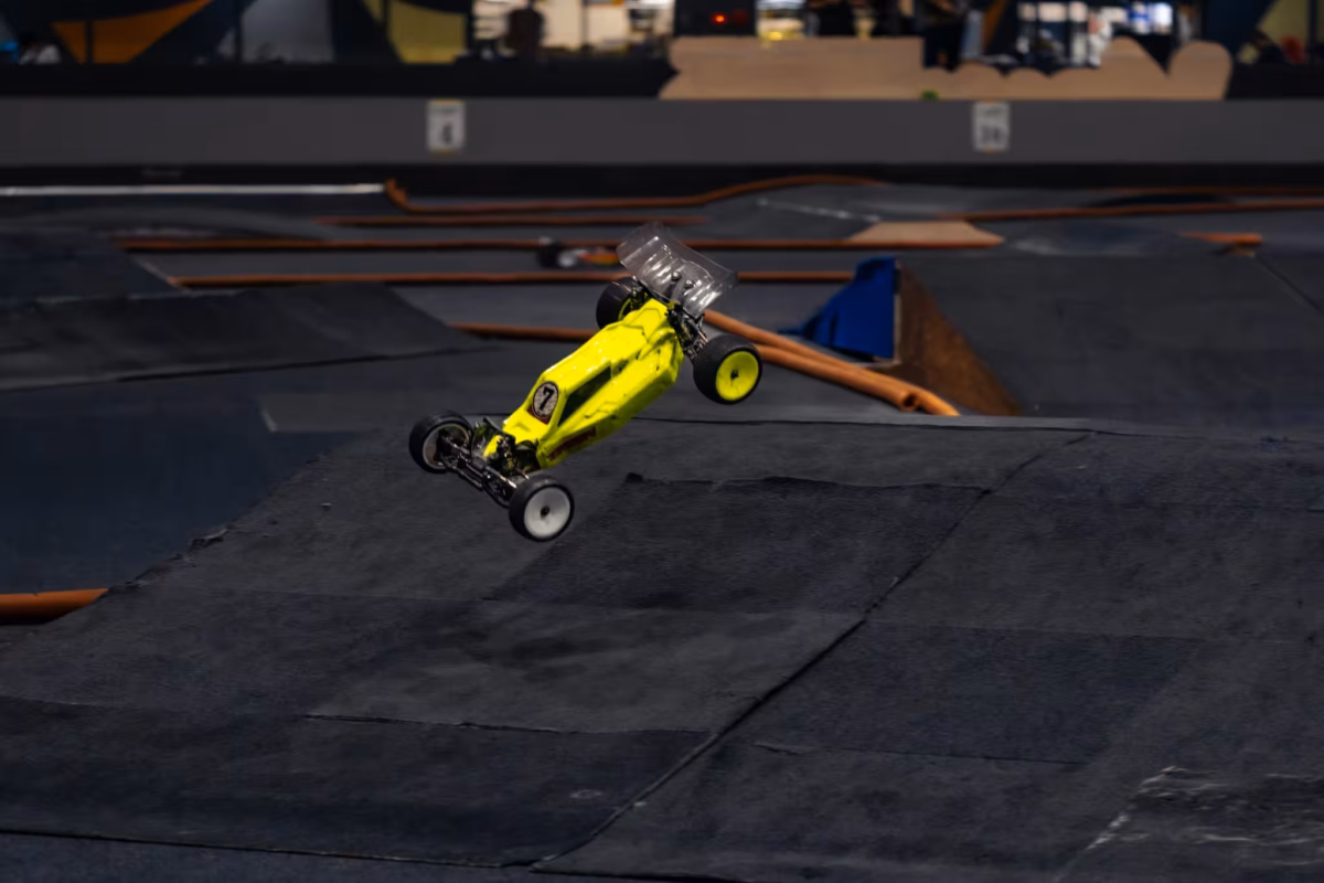 A yellow RC car flies over a jump.