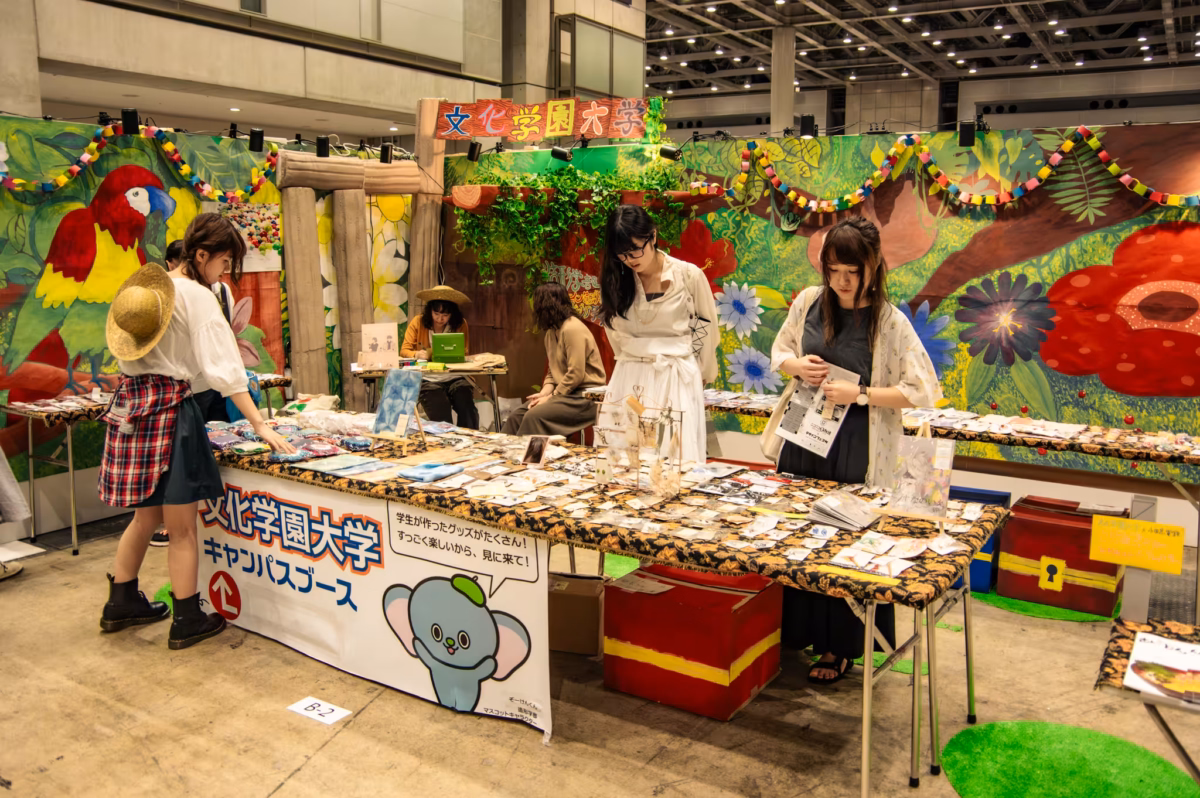 Women look at artwork on a table.