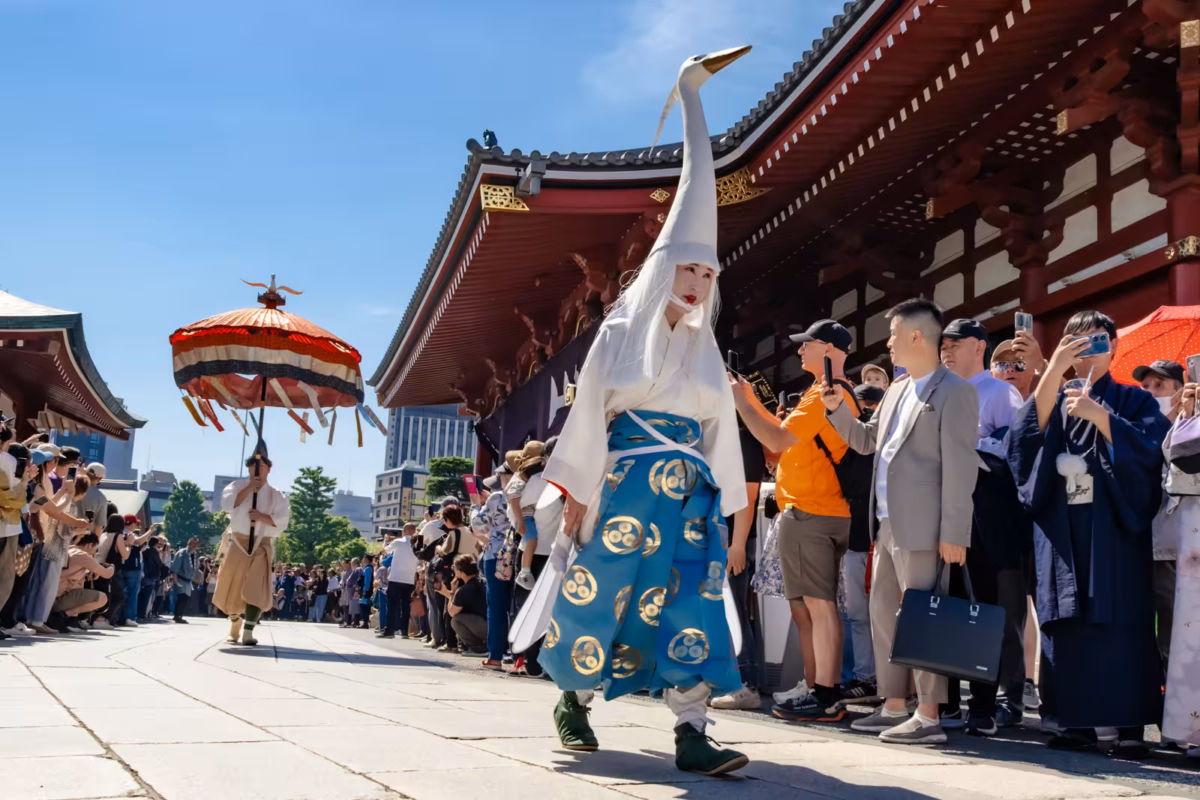 Shirasagi-no-mai dancer in a white heron costume parades past crowds at Senso-ji Temple in Asakusa, Tokyo.