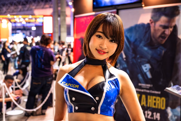 Capcom booth model in a blue and black outfit at Tokyo Game Show 2017 with a Resident Evil poster behind her.