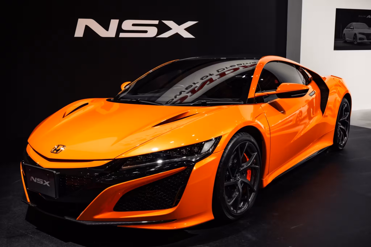 An orange Honda NSX in a black display booth.