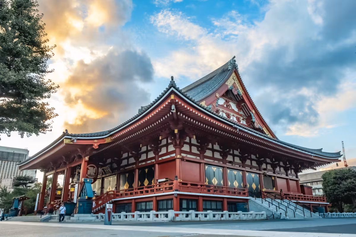 Senso-ji Temple in Asakusa, Tokyo, at sunset, featuring its iconic red architecture and a dramatic, cloudy sky.