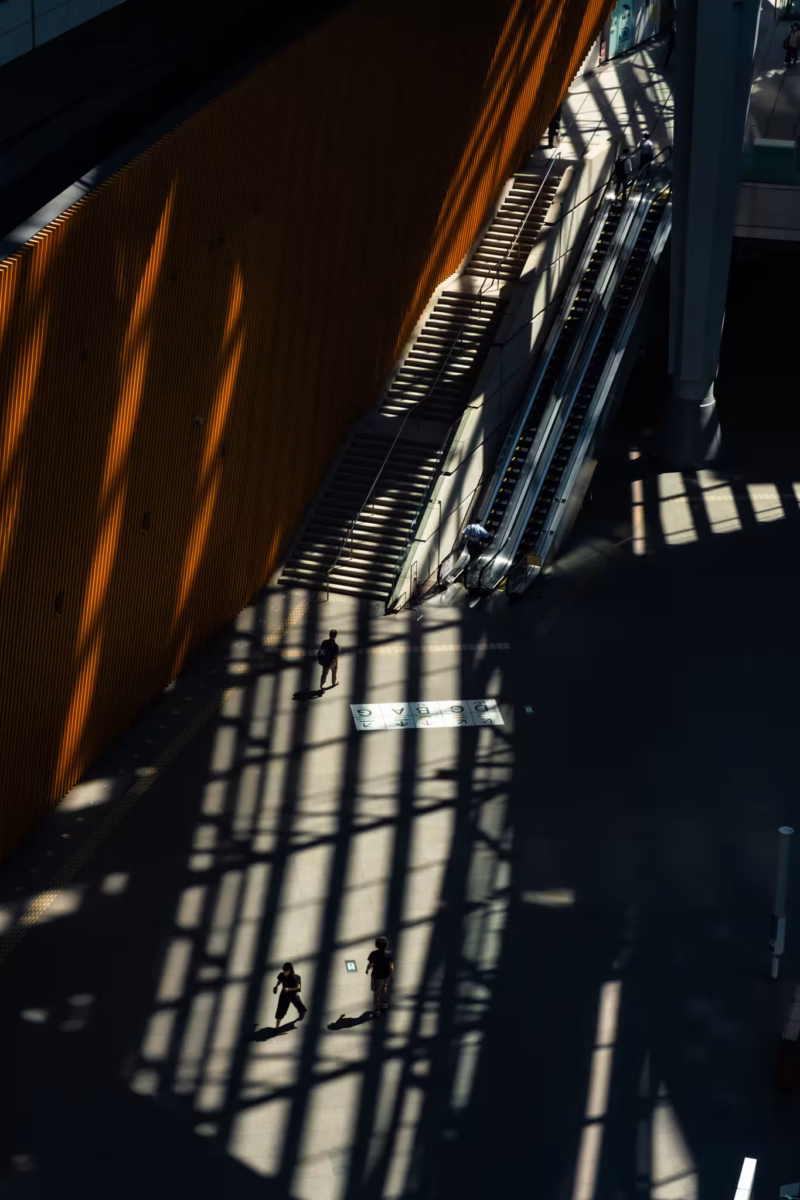Dramatic geometric shadows cast across the floor and escalators of the Tokyo International Forum.