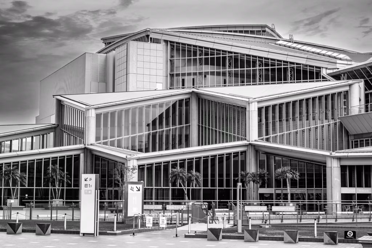 Black and white architectural shot of the angular glass and steel exterior of Tokyo Big Sight’s exhibition halls.
