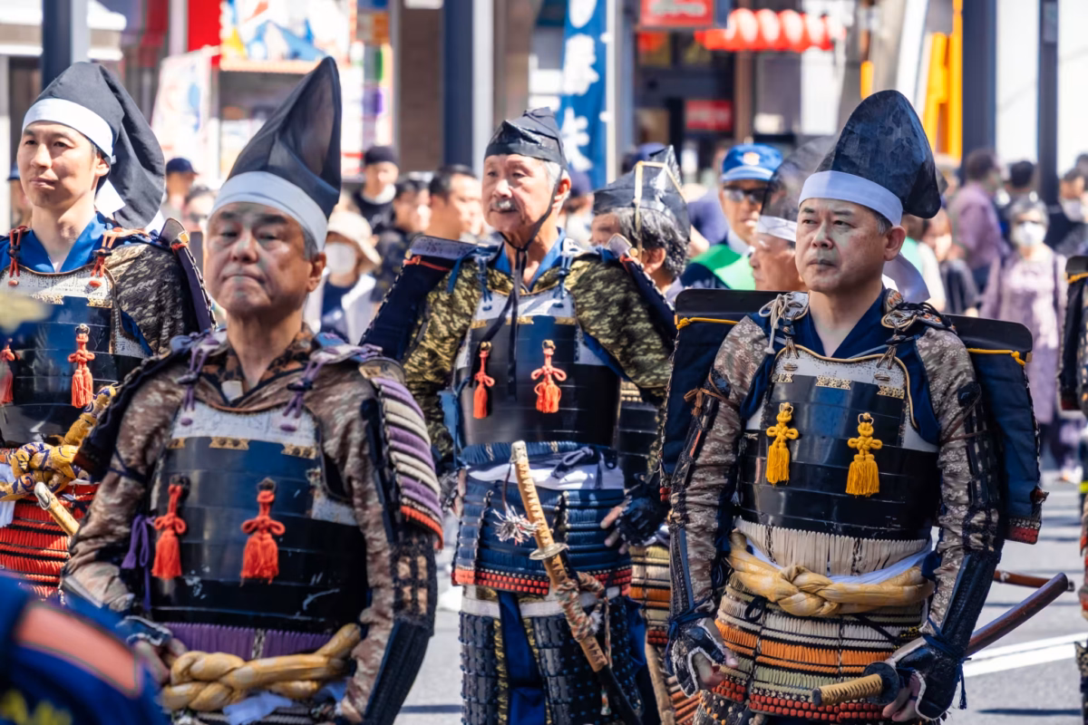 Men in Heian-period amor walk through a Tokyo during during the Kachiya Matsuri samurai parade.