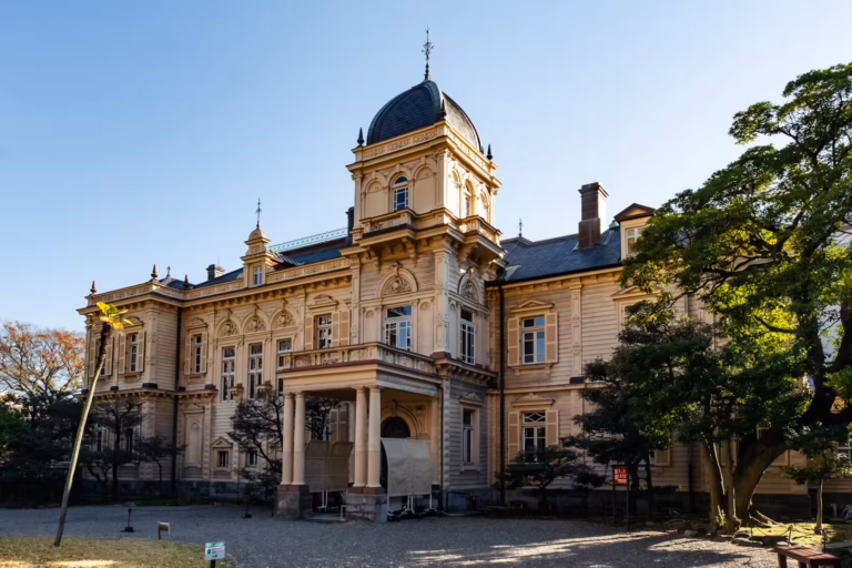 Historic Western-style mansion with a domed tower at Kyu-Iwasaki Gardens under a clear sky.