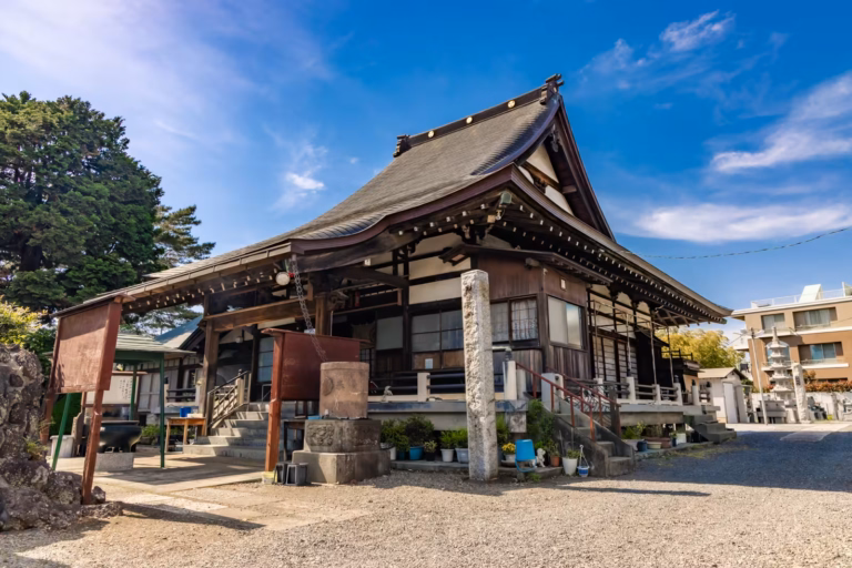 Traditional Japanese architecture of Kisshoin Temple with its dark wooden facade and sweeping roof under a blue sky.
