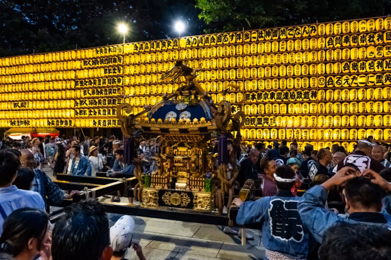 A golden mikoshi sits before a massive wall of glowing yellow paper lanterns at Mitama Festival 2017.