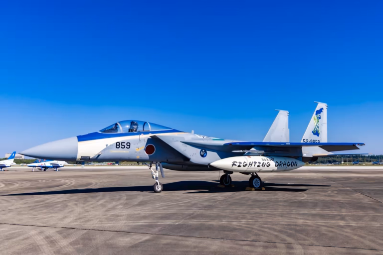 F-15J Eagle fighter jet marked "Fighting Dragon" on the tarmac at Iruma Air Show 2024 under a clear blue sky.