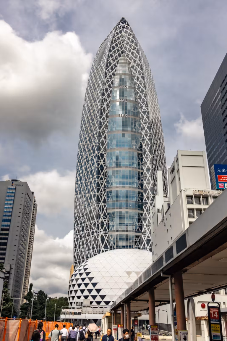 Mode Gakuen Cocoon Tower and its spherical dome base rise above a Shinjuku street against a cloudy sky.