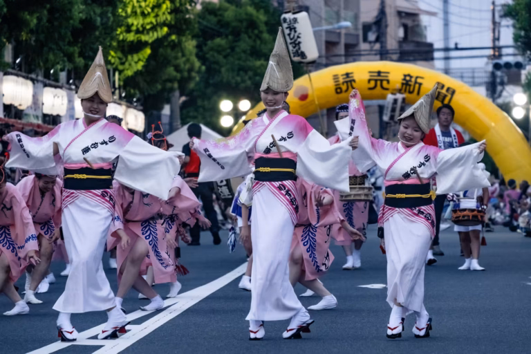 Dancers in pink and white kimonos and tall straw hats perform at the Koenji Awa Odori 2024 festival.