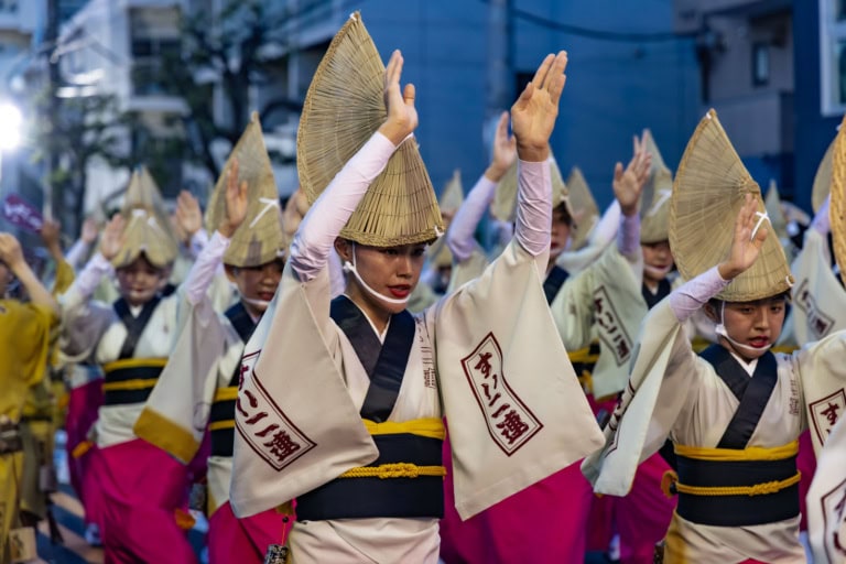 Women in traditional white and pink dress and amigasa hats perform at the Koenji Awa Odori 2025 street festival.
