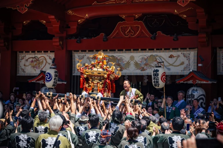 Crowds carry a golden mikoshi portable shrine during a lively festival celebration at Kanda Myojin.