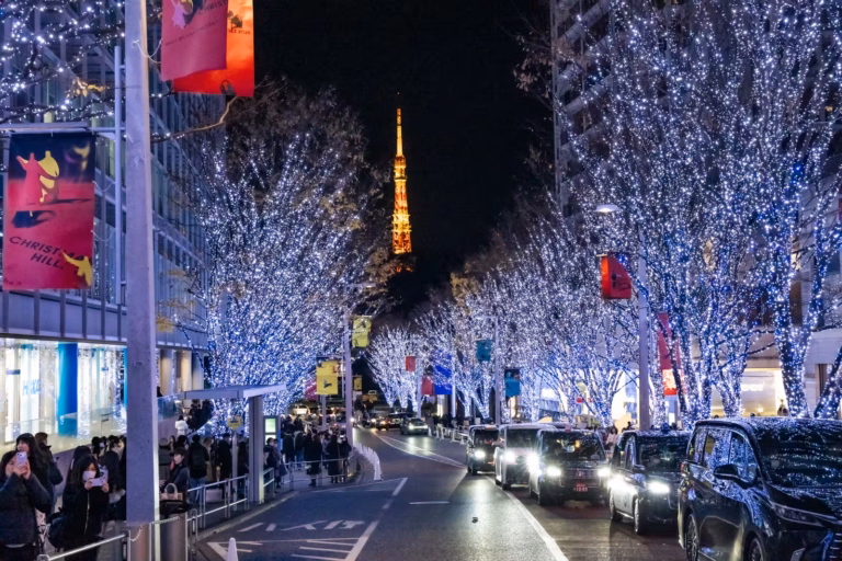 Sparkling blue holiday lights line Keyakizaka street at night, framing the warm glow of Tokyo Tower in the distance.