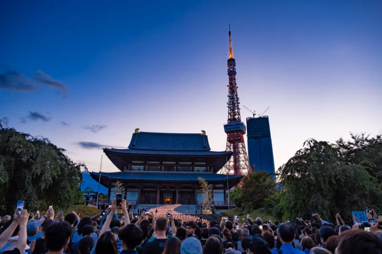 A crowd photographs the Zojoji Tanabata lanterns at dusk, with Tokyo Tower rising behind the temple.