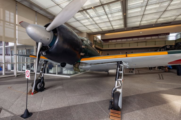 A Mitsubishi Zero fighter plane with a silver propeller on display at the Yushukan Museum.
