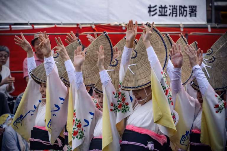 Dancers in traditional kimonos and woven straw hats perform with hands raised during the Koenji Awa Odori.