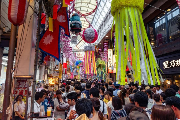 Crowds fill a shopping arcade decorated with colorful streamers and lanterns for the Asagaya Tanabata Festival.