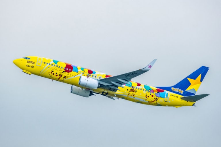 A yellow Skymark Airlines Pikachu Jet taking off at Haneda Airport, featuring colorful Pokémon balloon livery.