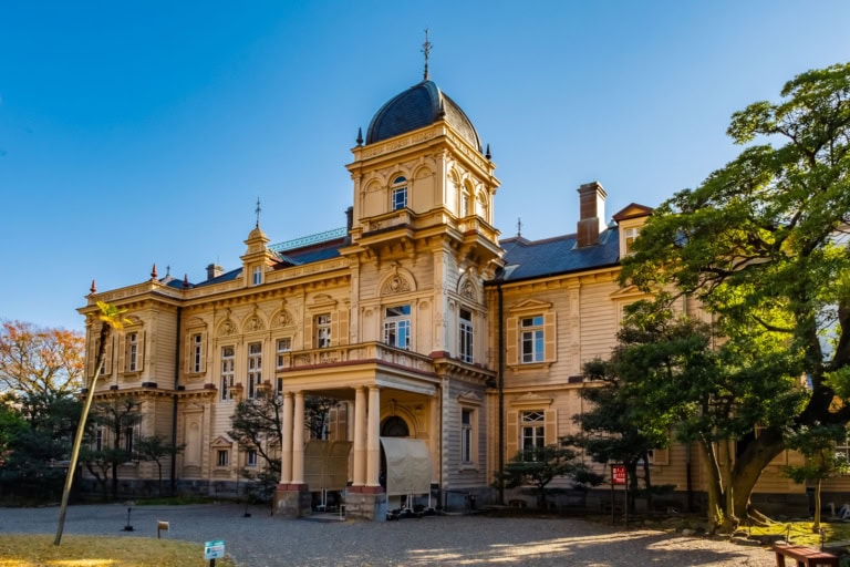 Historic Western-style mansion with a domed tower at Kyu-Iwasaki Gardens under a clear sky.