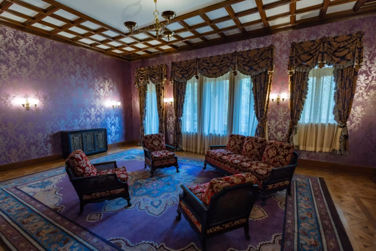 Maeda House sitting room with purple damask wallpaper, red floral furniture, and a dark wood coffered ceiling.